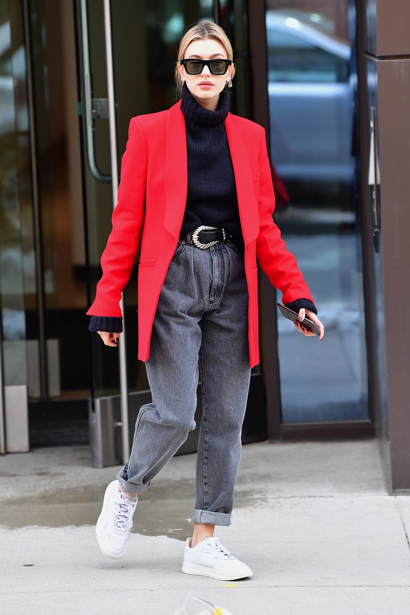 Elegant Hailey Bieber wearing a bright red jacket and adidas sneakers bringing coffee for Justin Bieber