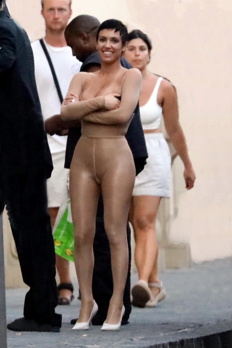 *PREMIUM-EXCLUSIVE* *MUST CALL FOR PRICING* Kanye West clutches a champagne bottle in the street as his wife bares all in a racy 'nude' catsuit.