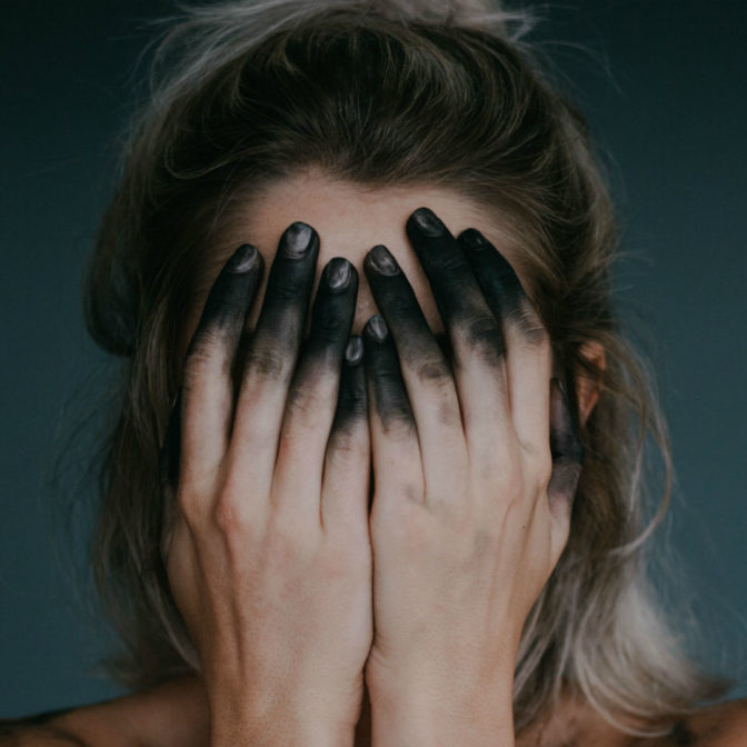 Dziewczyna zakrywa twarz dłońmi