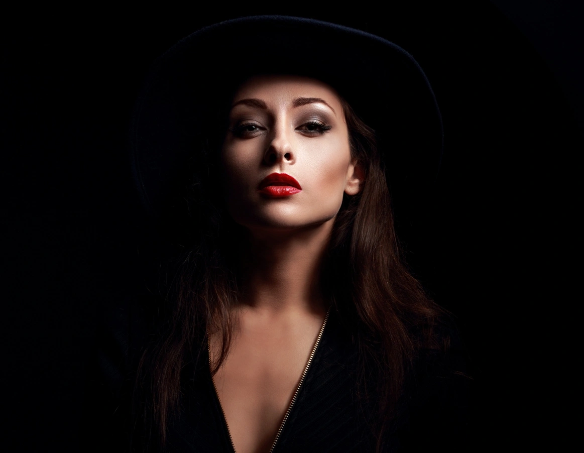 Kobieta przebrana za czarownicę na halloween z czerwonymi ustami i mocnym ciemnym makijażem oczu