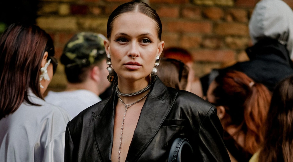 Kobieta w makijażu ze związanymi włosami pozuje z przedziałkiem na głowie