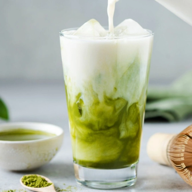 Zielona herbata, matcha z mlekiem w przezroczystej szklance.