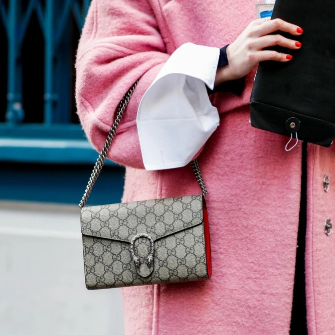 Kobieta pozuje na ulicy i prezentuje swoją stylizację z różowym płaszczem.