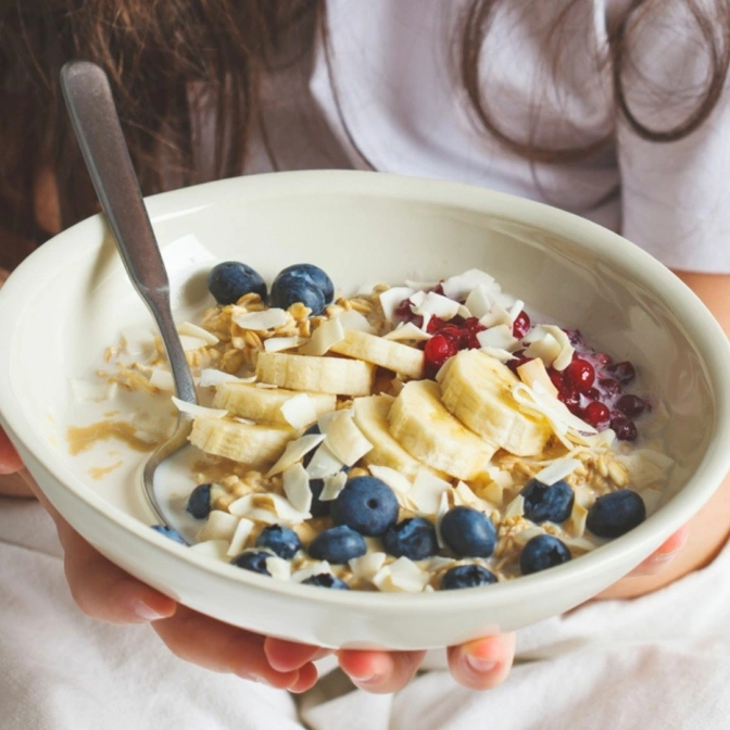 Kobieta trzyma w dłoniach talerz z owocami.